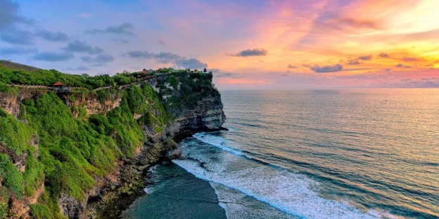 A cliff with a body of water and a sunset AI-generated content may be incorrect.