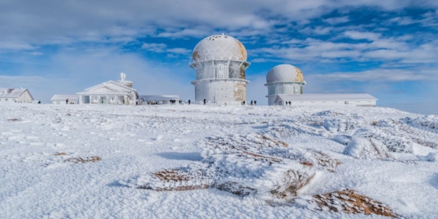 A snowy landscape with buildings and snow with Serra da Estrela in the background AI-generated content may be incorrect.