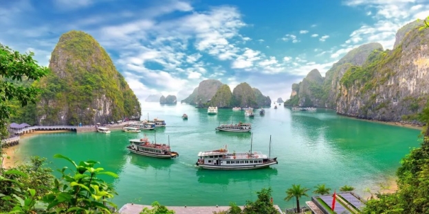 Boats in the water with boats with Ha Long Bay in the background AI-generated content may be incorrect.
