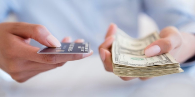 A person holding a credit card and a stack of money AI-generated content may be incorrect.