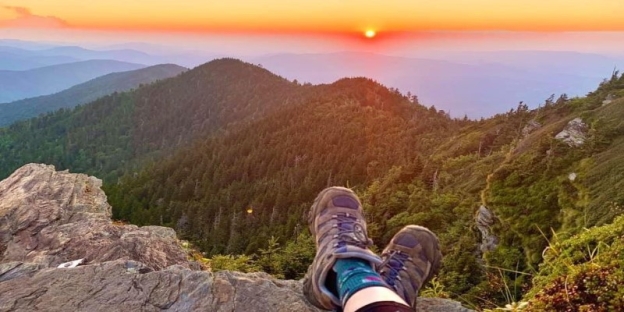 A person's legs on a rock overlooking a mountain range AI-generated content may be incorrect.