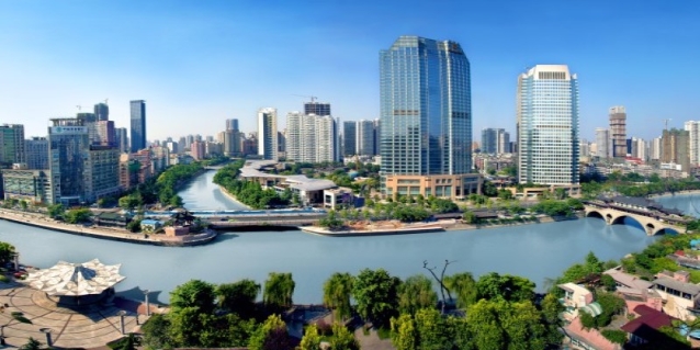 A river with trees and buildings in the background AI-generated content may be incorrect.